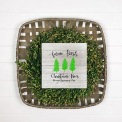 Tobaccoo basket with a boxwood wreath holding a wood sign saying Farm Fresh Christmas Trees.