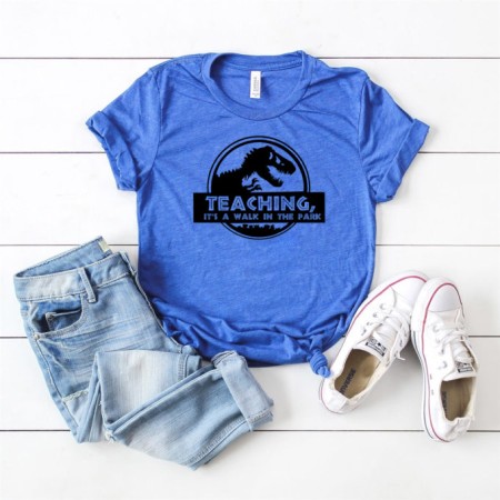blue shirt with a custom design featuring a dinosaur and the words teaching, its a walk in the park.