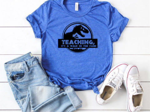 blue shirt with a custom design featuring a dinosaur and the words teaching, its a walk in the park.