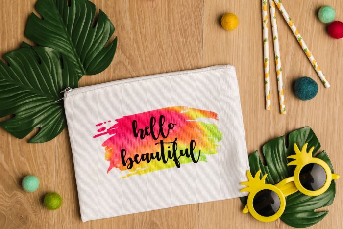 infusbile ink on a white makeupbag with a brush stroke design and the text hello beautiful written across it.