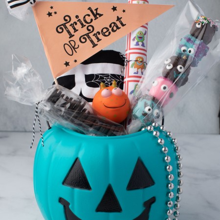 Pumpkin bucket filled with treats, games, and decorations