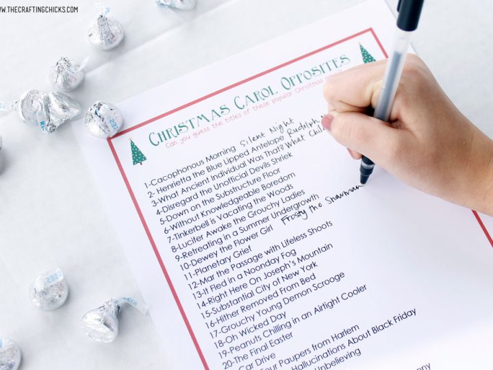 a paper with Christmas Carol games on a table with silver chocolates scattered around.