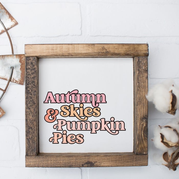 wood sign with pink gold and peach text stating Autumn Skies & pumpkin pies