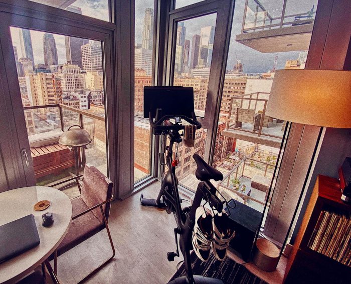 a peloton bike in a home gym facing a large window with a view of the city