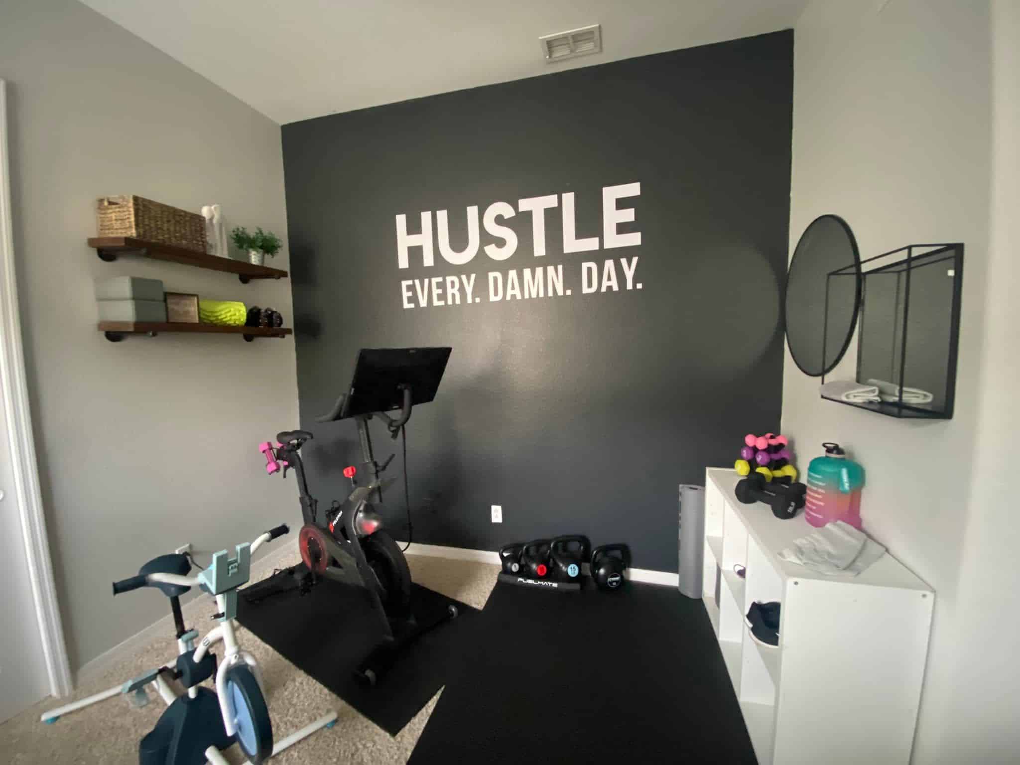 small home gym with peloton bike, kids pelican bike, and motivational quote