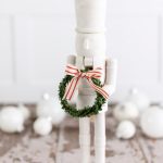 modern white nutcracker holding a wreath with a bow.