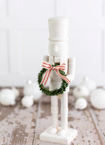 modern white nutcracker holding a wreath with a bow.