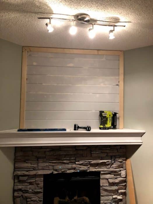 Stone corner fireplace with whitewashed stone. Process photo of adding shiplap to fill in the awkward space above the TV.