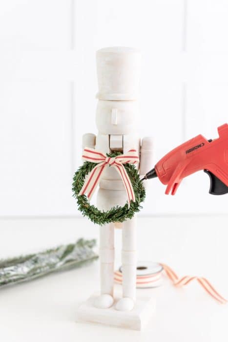 Attaching a tiny wreath to a farmhouse modern nutcracker.