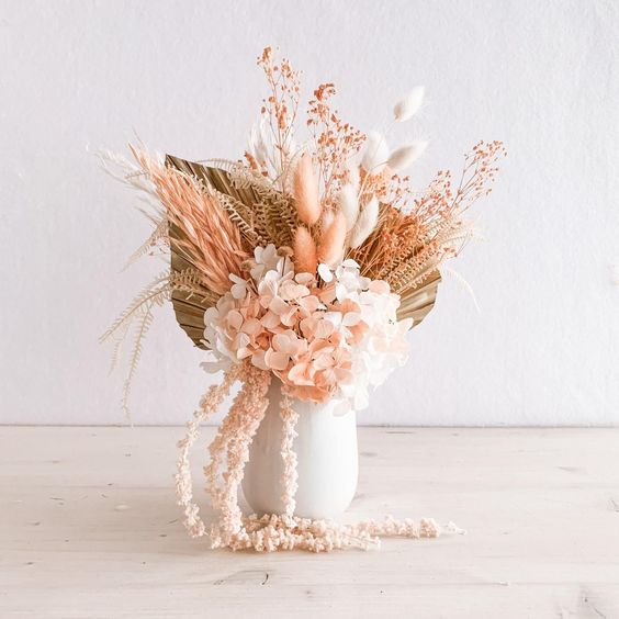 arrangement of neutral and light pink dried florals in a white vase.
