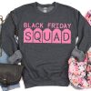grey womens sweatshirt with denim pants, a black purse and a scarf. The sweatshirt has pink text saying black friday squad.