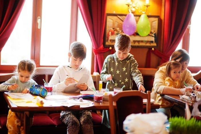 A group of kids coloring at a dining table in a restaraunt.