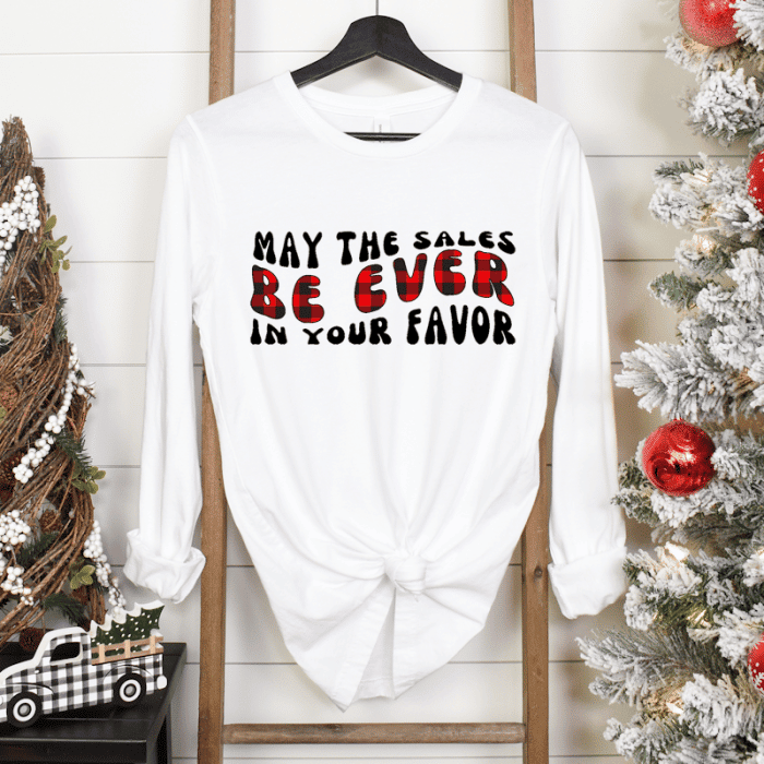 a white long sleeved shirt hanging on a wooden ladder leaning against a shiplap wall. There are christmas decorations one the side and a flocked christmas tree on the right.