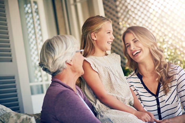 Three women in one family, a young girl sitting outside with her mother and grandmother.