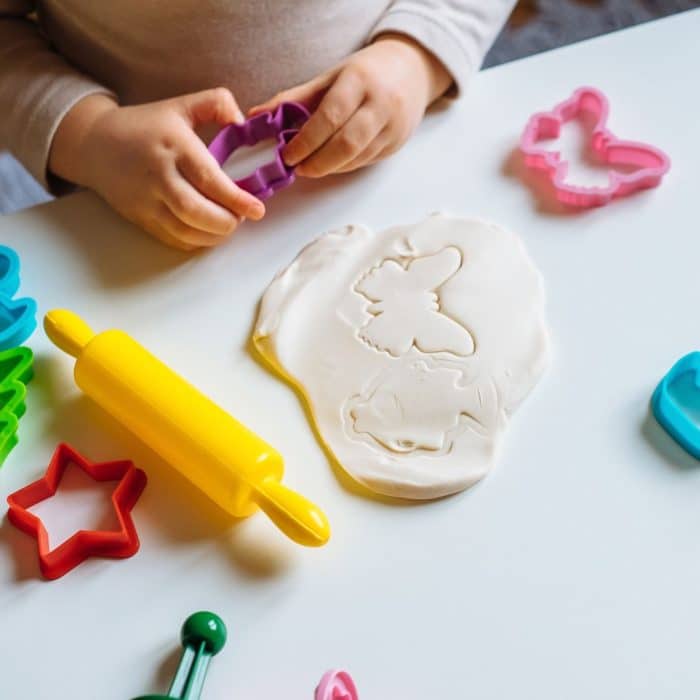 Plaudough being cut with small colorful cookie cutters.