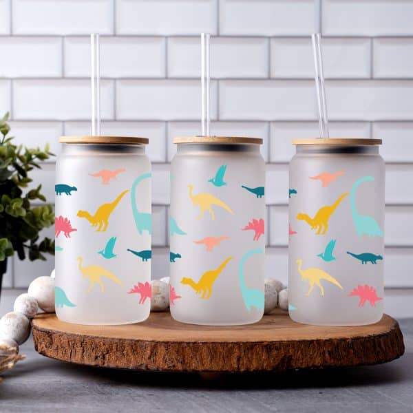 three frosted glass cups with vinyl decals of dinosaurs