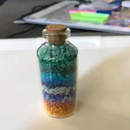 glass bottle with a cork stopper filled with leftover diamond dots drills.