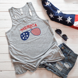 A mockup image showcasing a women's flowy racerback tank top with a 4th of July theme. The tank top is in a grey color and features a blue, red and white design on the front. You can make your own 4th of July tank top for celebrating Independence Day using this free SVG design.