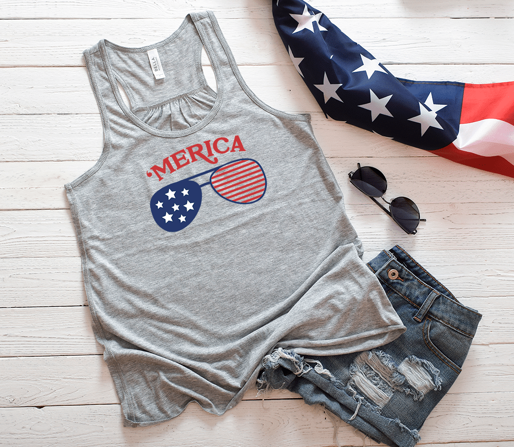 A mockup image showcasing a women's flowy racerback tank top with a 4th of July theme. The tank top is in a grey color and features a blue, red and white design on the front. You can make your own 4th of July tank top for celebrating Independence Day using this free SVG design.