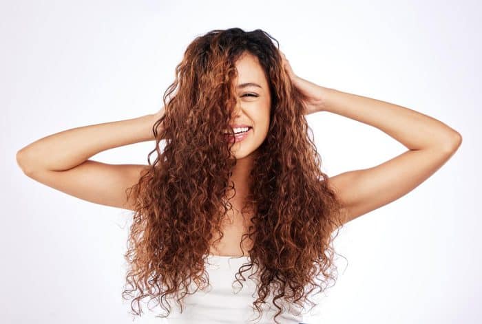 Portrait of a beautiful young woman showing off her natural curly hair against a white background.
