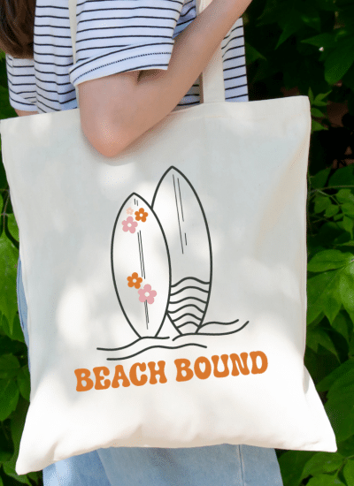 woman holding a tote bag with an image of surf boards and the text beach bound