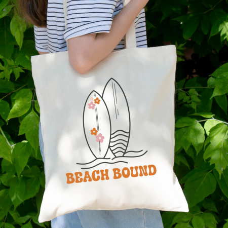 woman holding a tote bag with an image of surf boards and the text beach bound