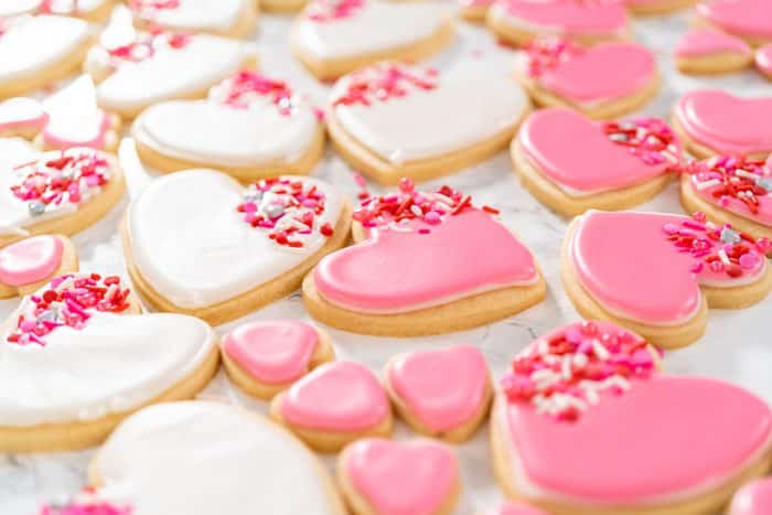 Decorating valentines sugar cookies with pink and white royal icing.
