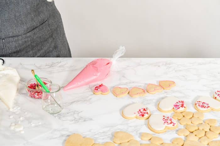 Decorating sugar cookies with pink and white royal icing for Valentine's Day.