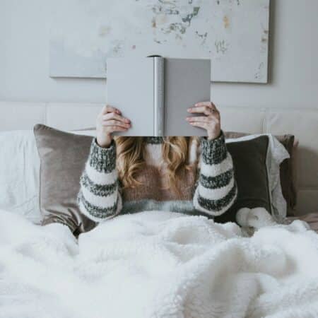 Woman in bed reading a book.
