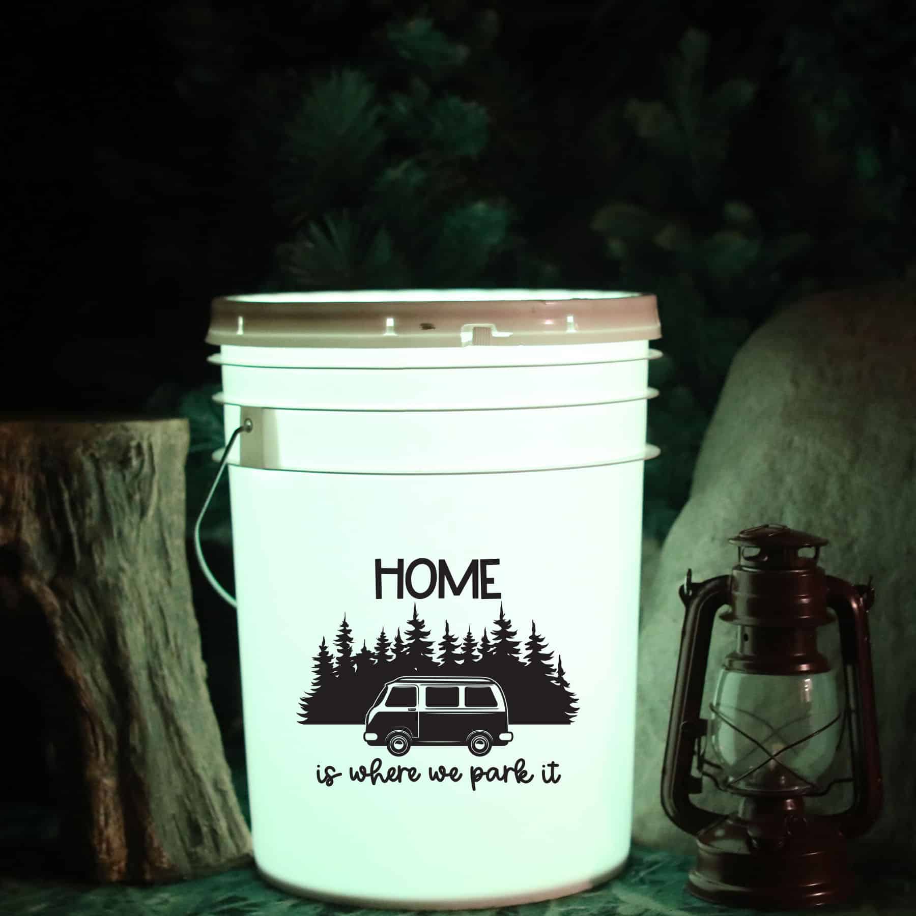 a cricut project using a bucket and led light to use for a camping light. Image shows a camper saying home is where we park it.